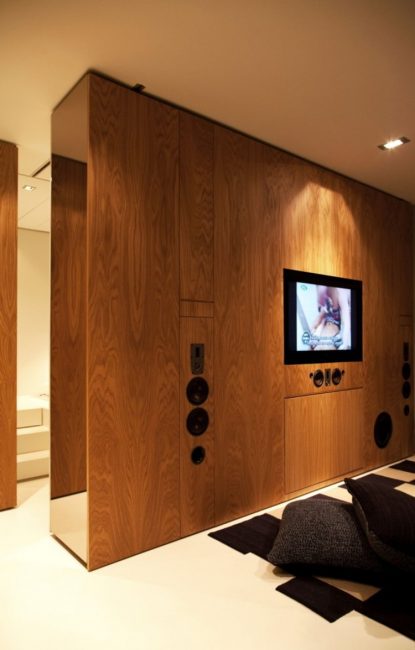 O painel de madeira para a TV divide a sala em diferentes zonas